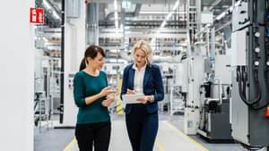 Businesswoman using tablet PC with coworker at factory